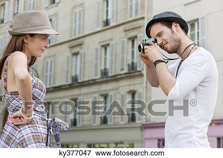 Man taking a picture of a woman standing with her hand on her hip, Paris, Ile-de-France, France View Large Photo Image Stock Photo - Man taking a picture of a woman standing with her hand on her hip, Paris, Ile-de-France, France. Fotosearch