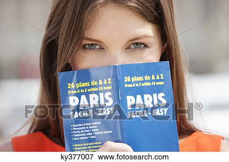 Portrait of a woman holding a travel guidebook in front of her face, Paris, Ile-de-France, France View Large Photo Image Stock Photo - Portrait of a woman holding a travel guidebook in front of her face, Paris, Ile-de-France, France. Fotosearch