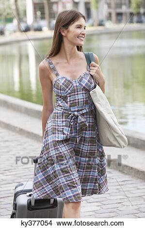 Picture - Woman pulling a suitcase and smiling, Paris, Ile-de-France, France. Fotosearch