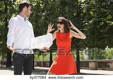 Picture - Woman shouting on a man reading a map, Terrasse De l'Orangerie, Jardin des Tuileries, Paris, Ile-de-France, France. Fotosearch