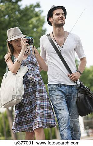 Stock Image - Woman walking on the road and photographing, Paris, Ile-de-France, France. Fotosearch
