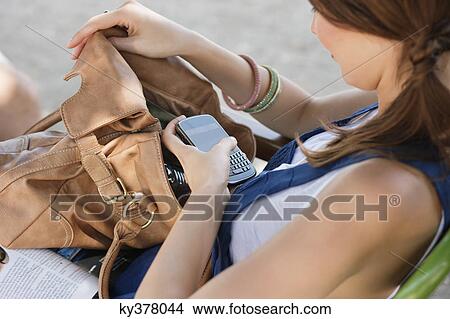 Woman checking her mobile in a purse, Paris, Ile-de-France, France View Large Photo Image Picture - Woman checking her mobile in a purse, Paris, Ile-de-France, France. Fotosearch