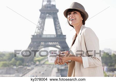 Picture - Woman holding a guide book with the Eiffel Tower in the background, Paris, Ile-de-France, France. Fotosearch