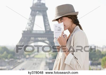 Woman holding a guide book with the Eiffel Tower in the background, Paris, Ile-de-France, France View Large Photo Image Stock Photo - Woman holding a guide book with the Eiffel Tower in the background, Paris, Ile-de-France, France. Fotosearch