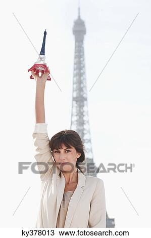 Woman holding a replica of the Eiffel Tower in front of the original one, Paris, Ile-de-France, France View Large Photo Image Stock Image - Woman holding a replica of the Eiffel Tower in front of the original one, Paris, Ile-de-France, France. Fotosearch