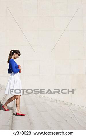 Stock Photo - Woman moving down steps, Paris, Ile-de-France, France. Fotosearch
