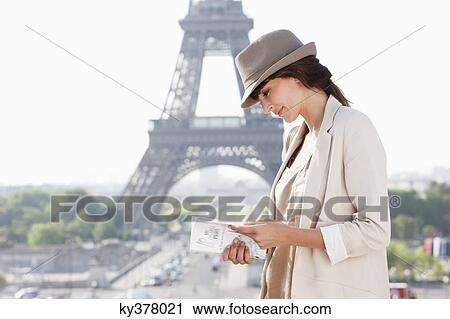 Stock Image - Woman reading a guide book with the Eiffel Tower in the background, Paris, Ile-de-France, France. Fotosearch