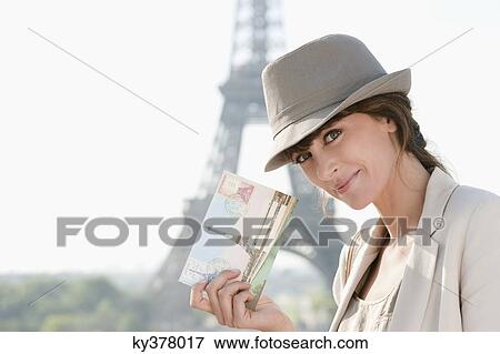 Stock Photo - Woman showing a postcard with the Eiffel Tower in the background, Paris, Ile-de-France, France. Fotosearch