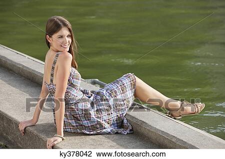 Woman sitting at the ledge of a canal and smiling, Paris, Ile-de-France, France View Large Photo Image Stock Image - Woman sitting at the ledge of a canal and smiling, Paris, Ile-de-France, France. Fotosearch