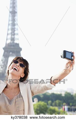 Stock Photo - Woman taking a picture of herself with the Eiffel Tower in the background, Paris, Ile-de-France, France. Fotosearch