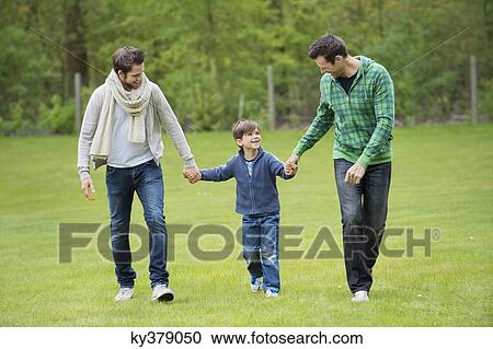 Boy walking with two men in a park View Large Photo Image Stock Image - Boy walking with two men in a park. Fotosearch