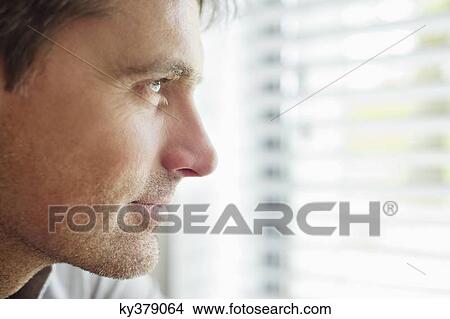 Close-up of a man looking through a window and thinking View Large Photo Image Picture - Close-up of a man looking through a window and thinking. Fotosearch