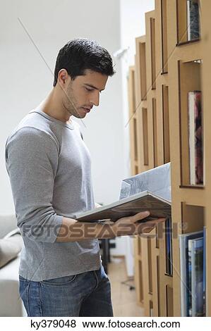 Stock Photo - Man choosing a book from a bookshelf. Fotosearch