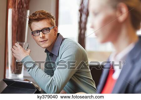 Man drinking water in a restaurant and looking at a businesswoman View Large Photo Image Stock Image - Man drinking water in a restaurant and looking at a businesswoman. Fotosearch