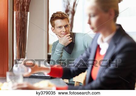 Man looking at a businesswoman having food in a restaurant View Large Photo Image Stock Photography - Man looking at a businesswoman having food in a restaurant. Fotosearch
