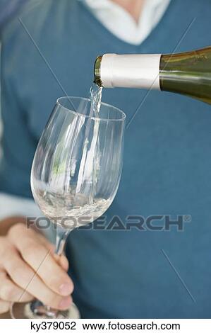 Stock Image - Man pouring wine in a wine glass. Fotosearch