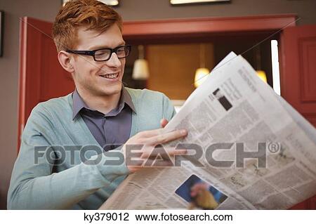 Stock Image - Man reading a newspaper in a restaurant. Fotosearch
