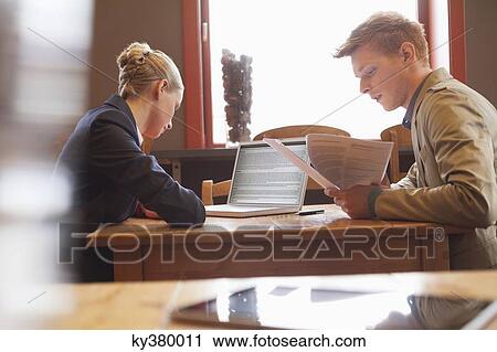 Business couple sitting in a restaurant and working View Large Photo Image Stock Image - Business couple sitting in a restaurant and working. Fotosearch