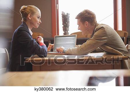 Business couple sitting in a restaurant using a laptop View Large Photo Image Stock Image - Business couple sitting in a restaurant using a laptop. Fotosearch