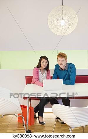 Business couple working on a laptop in an office View Large Photo Image Stock Photo - Business couple working on a laptop in an office. Fotosearch