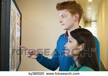 Stock Image - Business people looking at display screen. Fotosearch