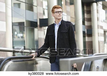 Businessman standing on escalator View Large Photo Image Stock Photo - Businessman standing on escalator. Fotosearch