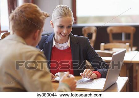 Couple sitting in a restaurant working on a laptop View Large Photo Image Picture - Couple sitting in a restaurant working on a laptop. Fotosearch