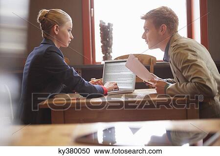 Couple sitting in a restaurant working on a laptop View Large Photo Image Stock Image - Couple sitting in a restaurant working on a laptop. Fotosearch