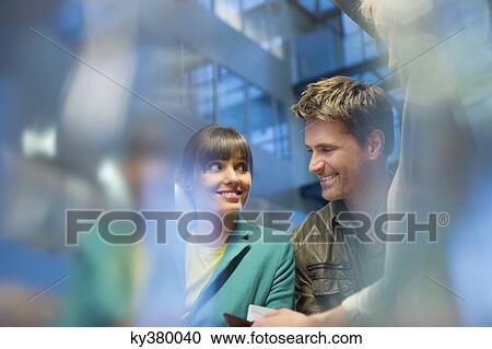 Stock Image - Happy couple standing at a checkout counter. Fotosearch