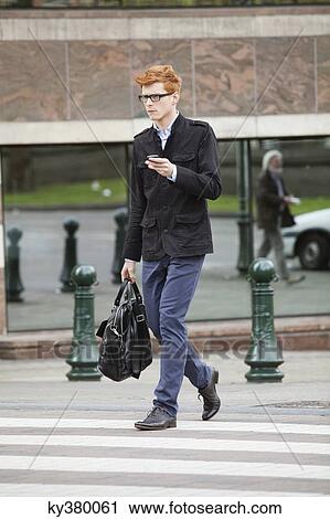 Man crossing the road while using a mobile phone View Large Photo Image Stock Image - Man crossing the road while using a mobile phone. Fotosearch