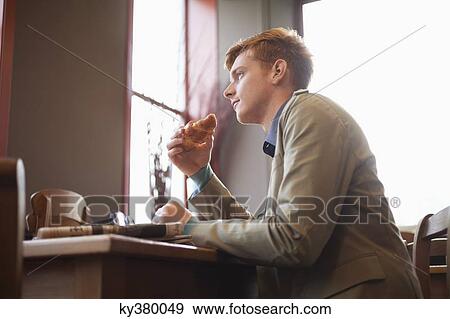 Stock Photo - Man eating croissant. Fotosearch