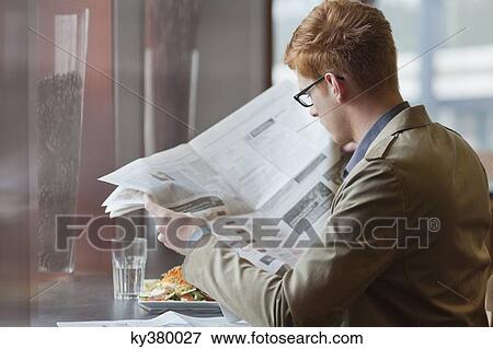 Man sitting in a restaurant and reading a newspaper View Large Photo Image Stock Photo - Man sitting in a restaurant and reading a newspaper. Fotosearch