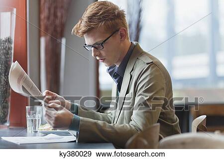 Stock Photo - Man sitting in a restaurant and reading a newspaper. Fotosearch