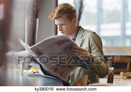 Stock Photograph - Man sitting in a restaurant and reading a newspaper. Fotosearch