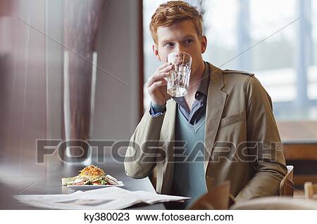 Stock Image - Man sitting in a restaurant and drinking water. Fotosearch