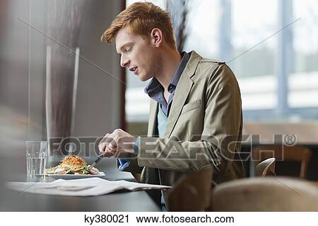 Stock Image - Man sitting in a restaurant taking lunch. Fotosearch