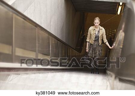Stock Photo - Businesswoman standing on escalator. Fotosearch
