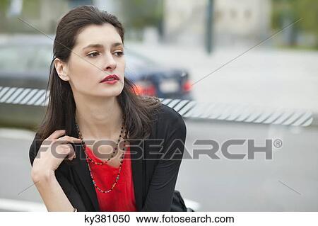 Stock Image - Close-up of a woman waiting at bus stop. Fotosearch