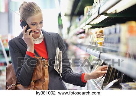 Woman in a supermarket talking on a mobile phone View Large Photo Image Stock Image - Woman in a supermarket talking on a mobile phone. Fotosearch