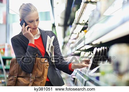 Woman in a supermarket talking on a mobile phone View Large Photo Image Stock Image - Woman in a supermarket talking on a mobile phone. Fotosearch