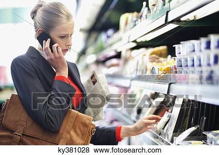 Woman in a supermarket talking on a mobile phone View Large Photo Image Stock Photo - Woman in a supermarket talking on a mobile phone. Fotosearch