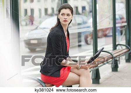 Woman sitting at a bus stop View Large Photo Image Picture - Woman sitting at a bus stop. Fotosearch
