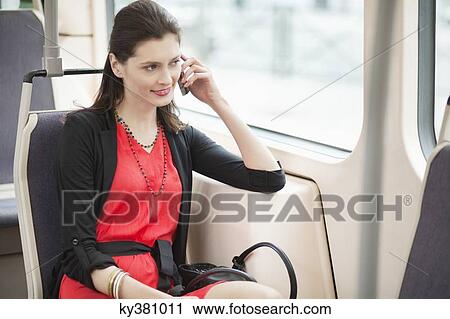 Woman traveling in a tram and talking on a mobile phone View Large Photo Image Stock Image - Woman traveling in a tram and talking on a mobile phone. Fotosearch