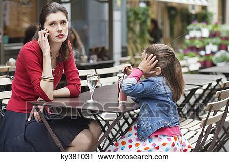Woman with her daughter sitting in a cafe View Large Photo Image Stock Image - Woman with her daughter sitting in a cafe. Fotosearch