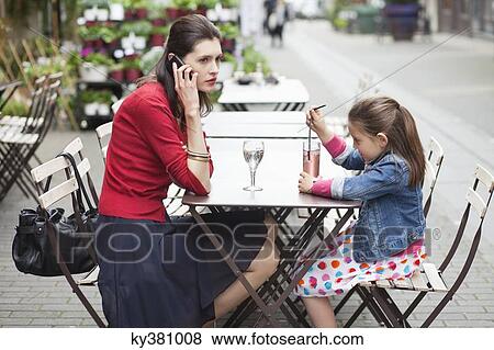 Woman with her daughter sitting in a cafe View Large Photo Image Stock Photo - Woman with her daughter sitting in a cafe. Fotosearch