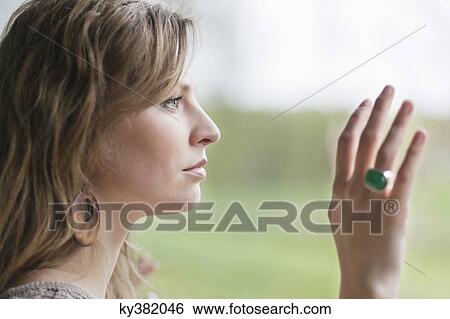 Close-up of a woman looking through the glass of a window View Large Photo Image Stock Photograph - Close-up of a woman looking through the glass of a window. Fotosearch