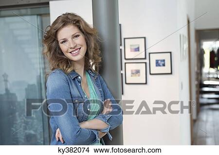 Picture - Happy woman leaning against a column. Fotosearch
