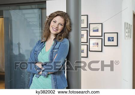 Stock Image - Happy woman leaning against a column. Fotosearch