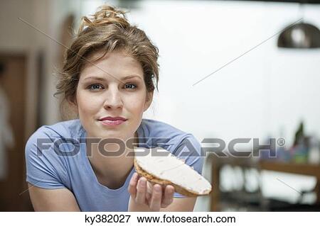 Stock Photo - Portrait of a woman eating toast with cream spread on it. Fotosearch