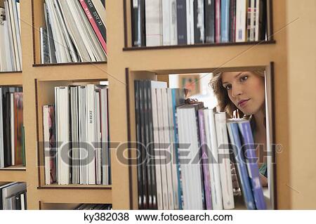 Woman choosing books from a bookshelf View Large Photo Image Stock Photo - Woman choosing books from a bookshelf. Fotosearch